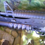 Buy Colt Commando clone XM177-style 5.56 rifle online featuring retro Vietnam-inspired tactical styling, Spikes Havoc launcher, battleworn Cerakote finish, and premium custom rifle upgrades.